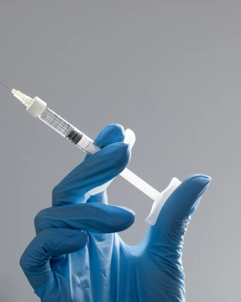 Gloved hand holding a syringe